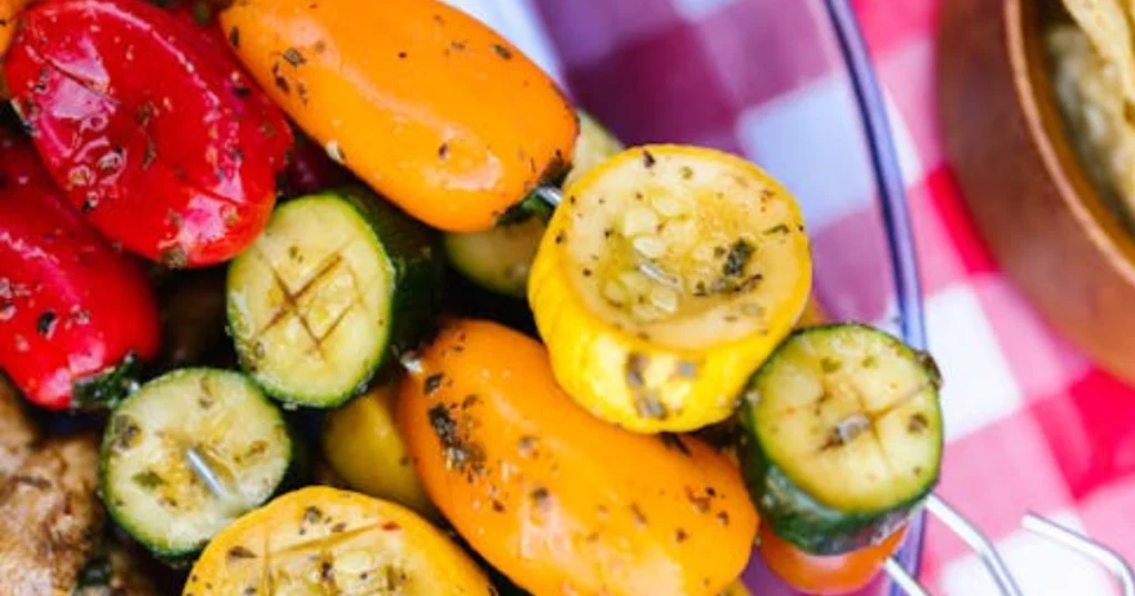 "An assortment of grilled vegetables including bell peppers, zucchini, eggplant, and onions, lightly charred and arranged on a platter, showcasing vibrant colors and textures