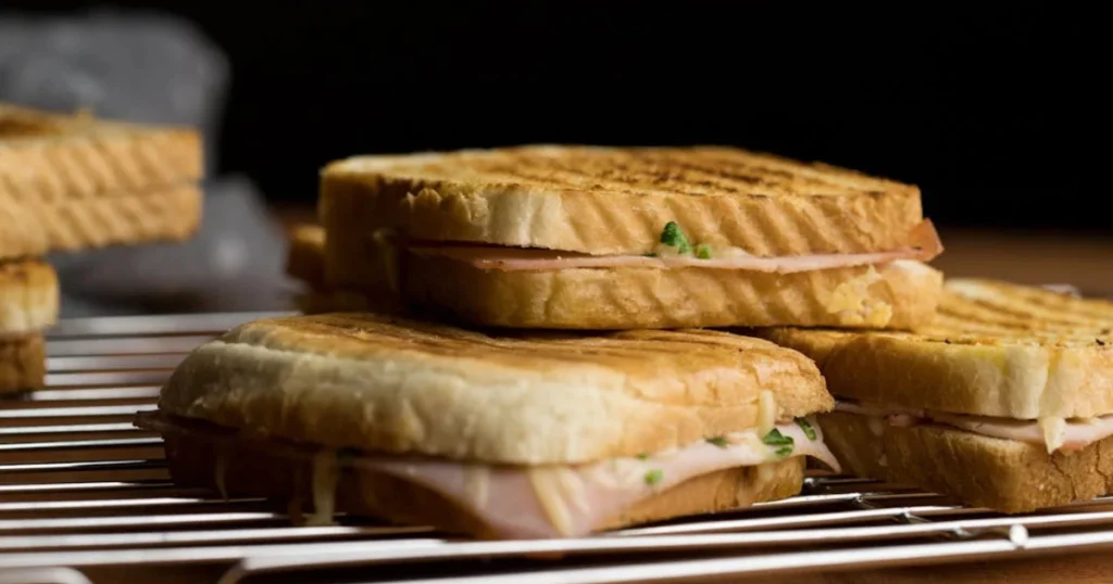 Golden, crispy grilled cheese sandwich with melted cheese oozing from the middle, served on a plate with a side of fresh salad.