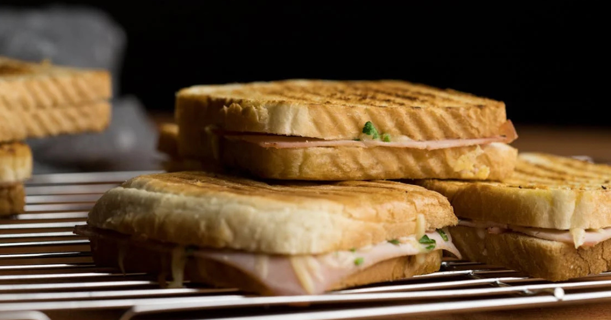 Golden, crispy grilled cheese sandwich with melted cheese oozing from the middle, served on a plate with a side of fresh salad.