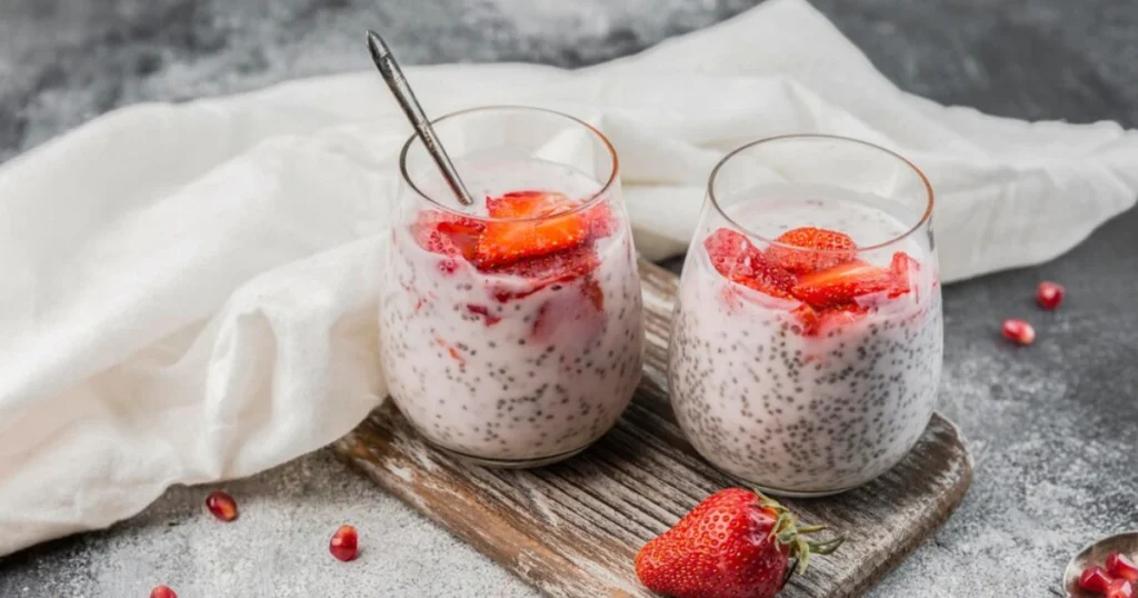 A close-up of chia seed pudding layered with almond milk and topped with toasted nuts and raspberries.