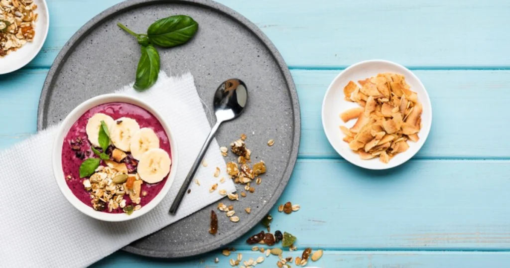 Nutritious Smoothie Bowl with Banana and Almond Butter, blueberries, granola, and banana slices on top