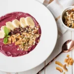 Smoothie Bowl with Banana and Almond Butter topped with fresh blueberries, granola, and banana slices.